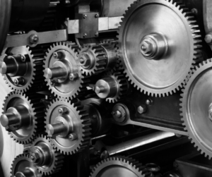 Black and white image of an assortment of interlocking metal gears and machinery parts.